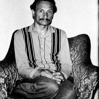 Man in striped shirt seated on armchair.
