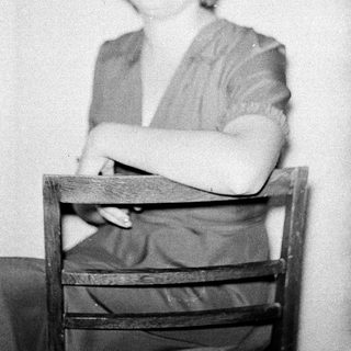 Black-and-white portrait of woman seated on chair.