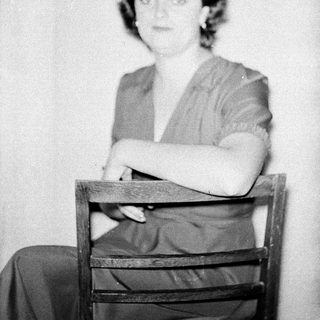 Black-and-white portrait of woman seated on chair.