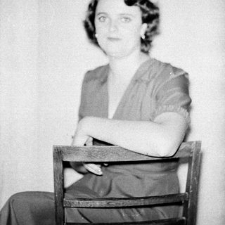 Black-and-white portrait of woman seated on chair.