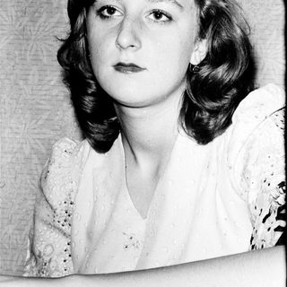 Young woman with shoulder-length curly hair in vintage-style portrait.