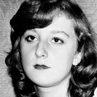 Young woman with shoulder-length curly hair in vintage-style portrait.