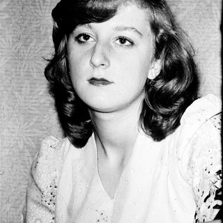 Young woman with shoulder-length curly hair in vintage-style portrait.