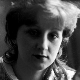 Young woman in checkered blouse, mid-20th century portrait.