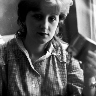 Young woman in checkered blouse, mid-20th century portrait.