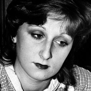 Woman in checkered blouse looking downward intently.