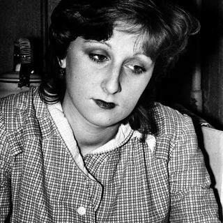Woman in checkered blouse looking downward intently.