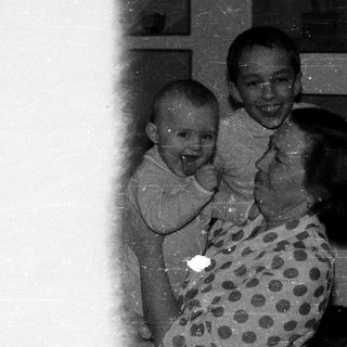 Three people laughing indoors, mid-1900s.