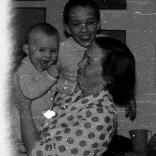 Three people laughing indoors, mid-1900s.