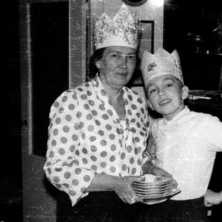 A woman and child dressed as chefs holding plates.