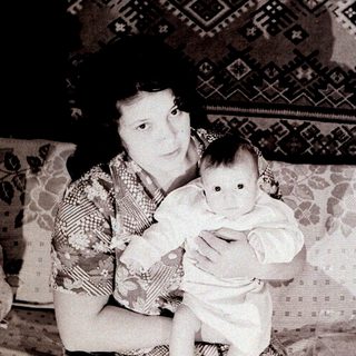 A woman holding a baby indoors.