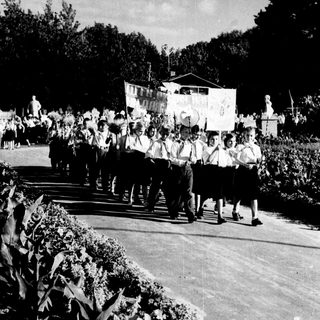 Group marching in outdoor parade with banners.