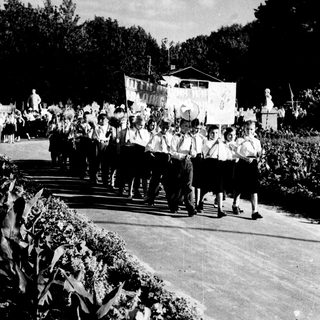 Group marching in outdoor parade with banners.