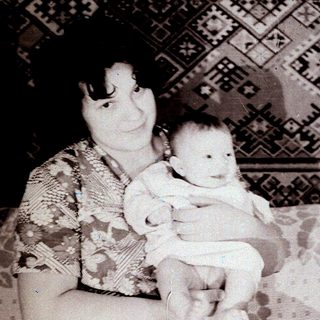 A woman holding a baby indoors.