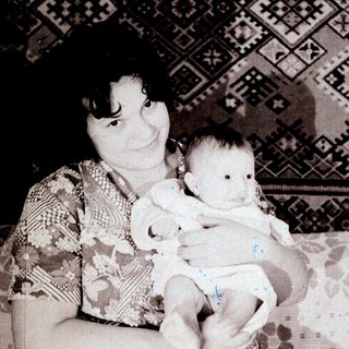 A woman holding a baby indoors.