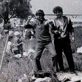 People clearing debris in an outdoor, damaged area.