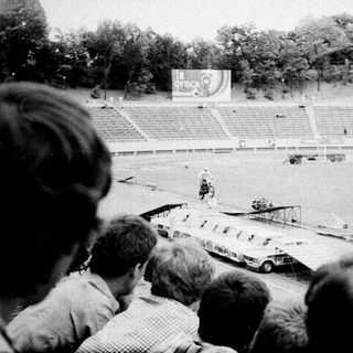 Spectators watch vintage aircraft display at stadium event.