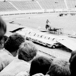 Spectators watch vintage car stunt show.