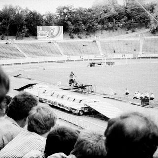 Spectators watch vintage car stunt show.