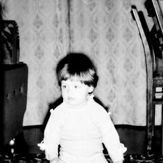 Young child sitting on patterned carpet.