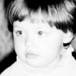 Young child sitting on patterned carpet.