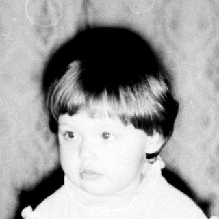 Young child sitting on patterned carpet.