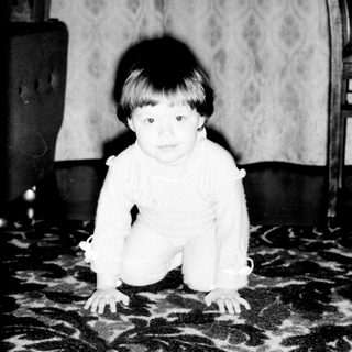 Baby crawling on patterned carpet indoors.