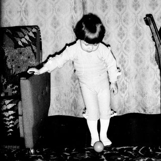 Toddler balancing on a ball indoors.