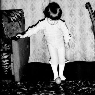 Toddler balancing on a ball indoors.