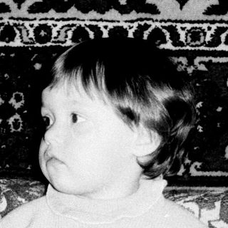 Young child sitting on vintage patterned sofa with toy.