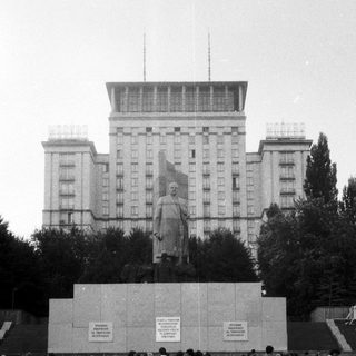Monument with statue of Soviet leader in urban plaza.