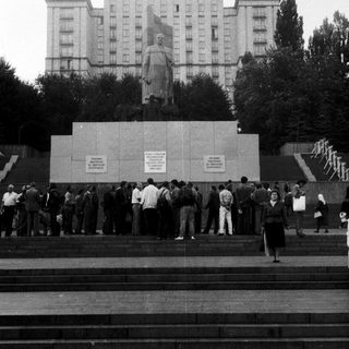 Monument with statue of Soviet leader in urban plaza.