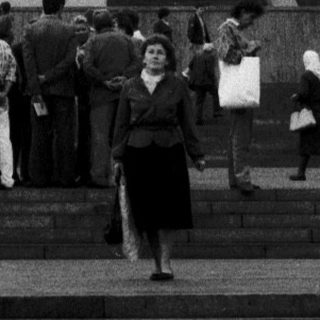 Monument with statue of Soviet leader in urban plaza.