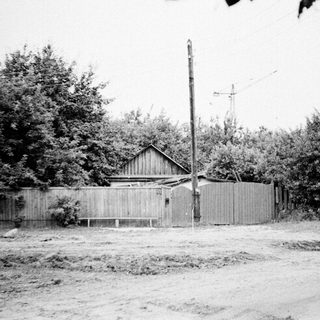 Rural house with wooden fence and overgrown yard.