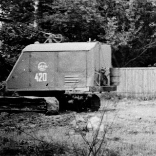 Military tank near fenced property with logs.