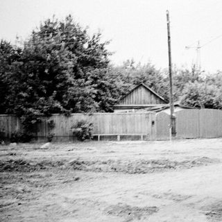 Rural house surrounded by wooden fence and trees.