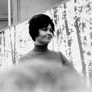 Woman posing indoors near abstract patterned wall.