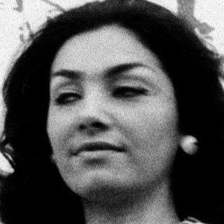Woman in striped blouse holding flowers outdoors.