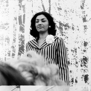 Woman in striped blouse holding flowers outdoors.
