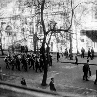 Military parade with spectators in urban setting.
