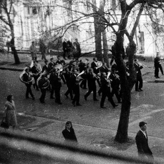 Military parade with spectators in urban setting.