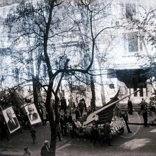 Historic street parade with military tanks and portraits.
