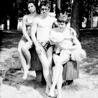 Four people posing outdoors near a tree.