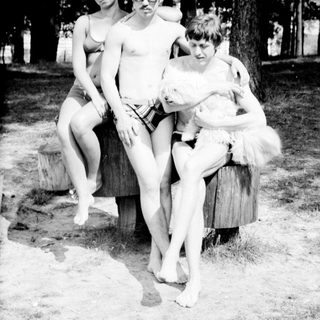 Four people posing outdoors near a tree.