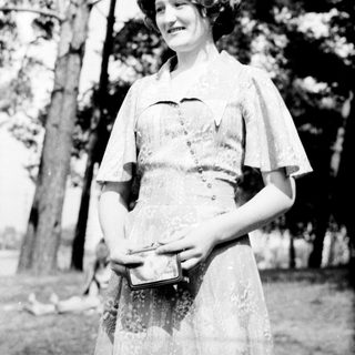 Nurse in vintage uniform holding medical box outdoors.