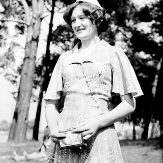 Nurse in vintage uniform holding medical box outdoors.
