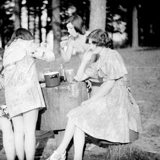 Group of people camping, preparing food outdoors.