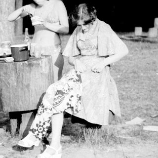 Four people outdoors by a barrel, likely washing clothes.