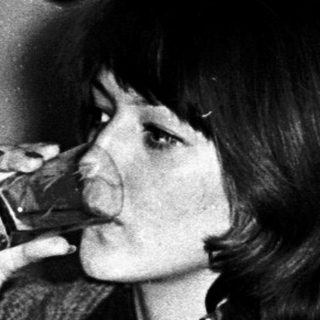 Woman drinking from a glass indoors.