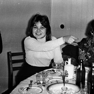Two women laughing together at a dinner table.